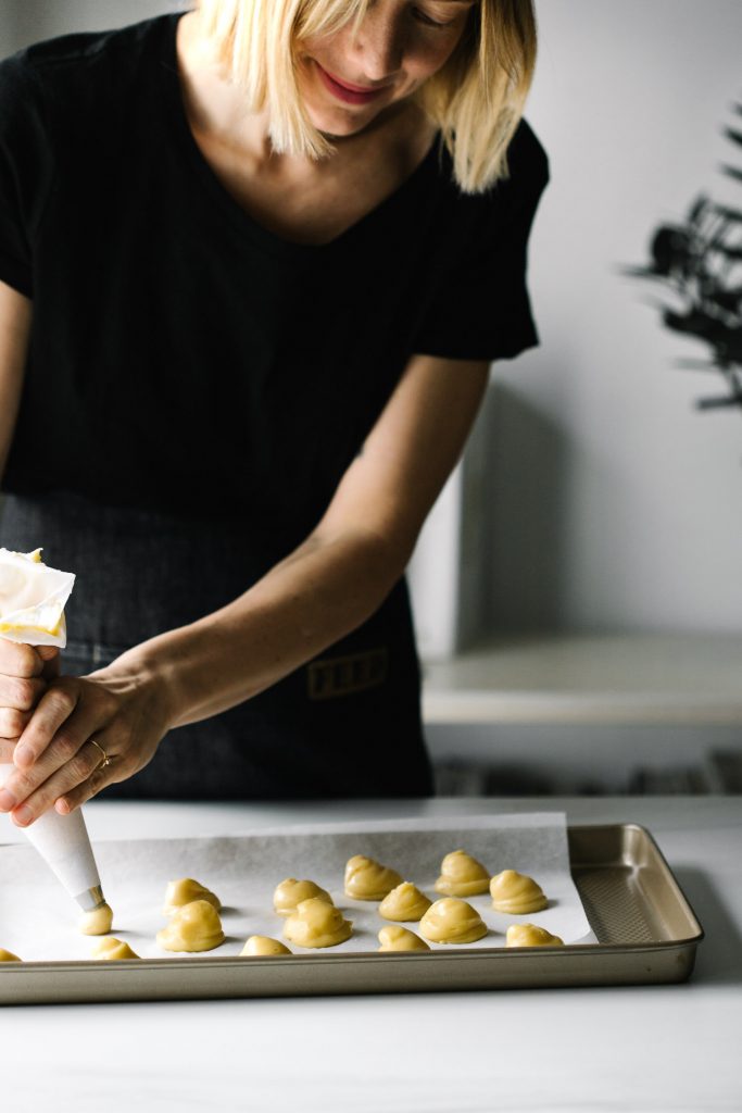 Shot of woman piping choux paste onto a baking sheet