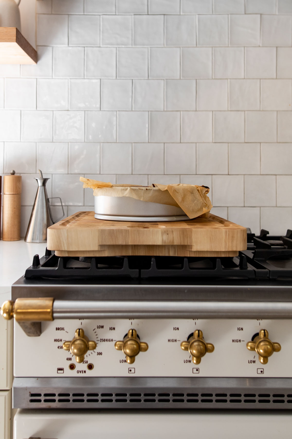 Springform pan with parchment paper on a wooden cutting board, placed on a Lacanche range.